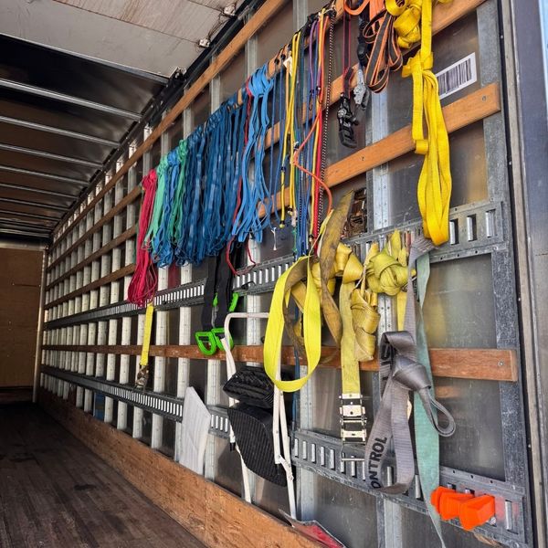 The organized interior of a moving truck featuring a variety of heavy-duty colorful ratchet straps and secure tie-down equipment. The organized interior of a moving truck featuring a variety of heavy-duty colorful ratchet straps and secure tie-down equipment.