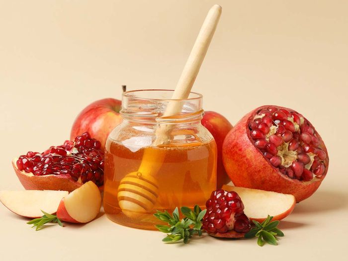Apple, honey and pomegranate on beige background