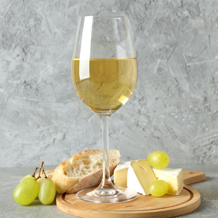 Chardonnay on a board with grapes, bread, and brie wedges