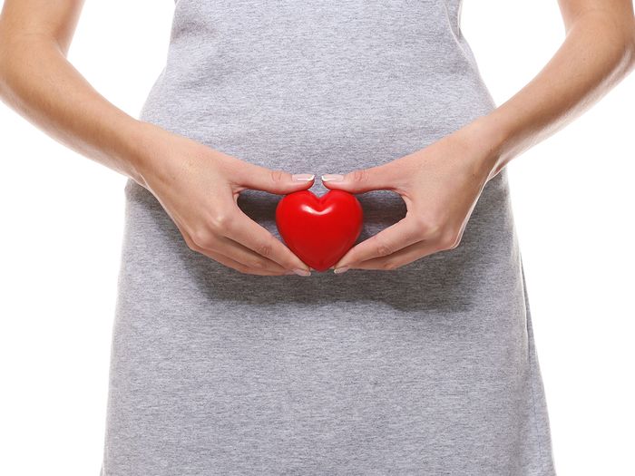  Woman holding a heart over her pelvic area. 