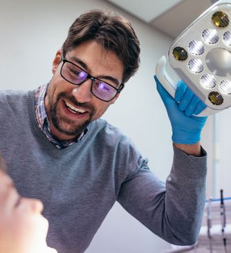 Dentist smiling at his young patient during exam