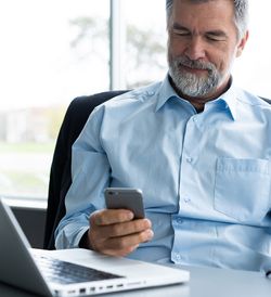 Older man using smartphone at his desk