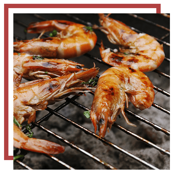 An image of 5 large prawns on a charcoal grill 
