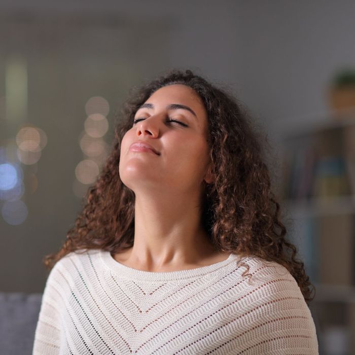 a happy woman taking a deep breath at home