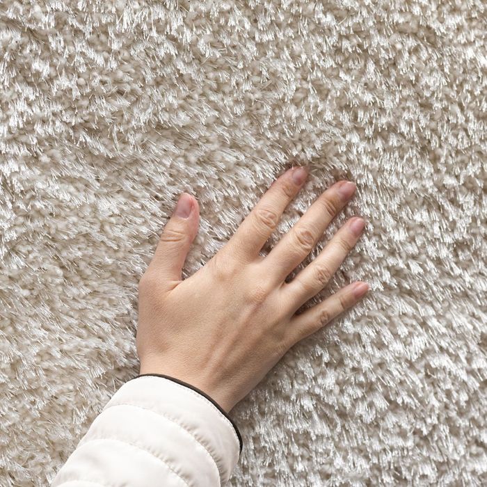 a person touching a plush clean carpet