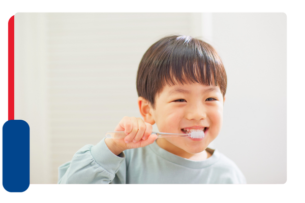 A young boy smiling while brushing his teeth