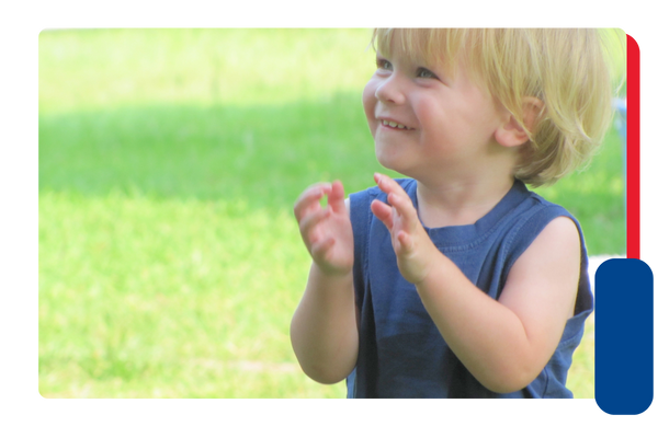 A young boy smiles and claps his hands together