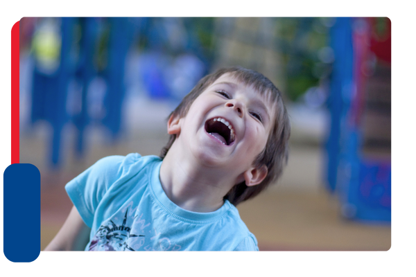 A young boy tilts his head back and smiles and laughs