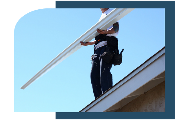 Man standing on roof, holding a new gutter