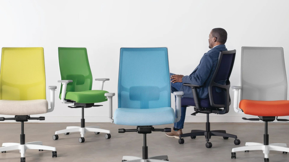 man sitting in chair with other office chairs around him