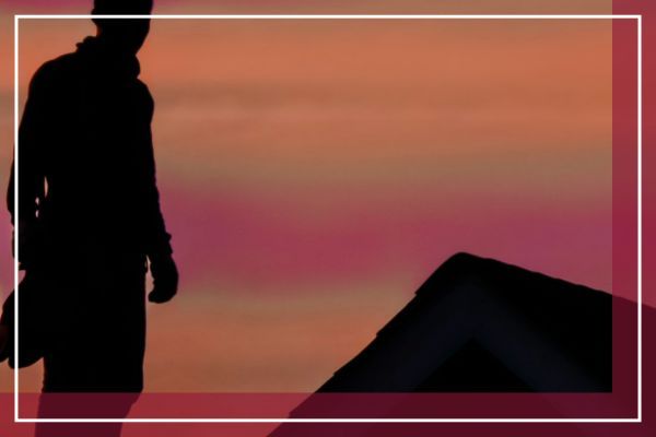 A roofer standing on a roof with a sunset in the background