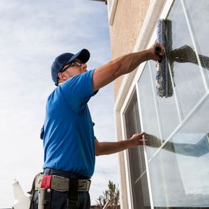 worker cleaning windows for a business