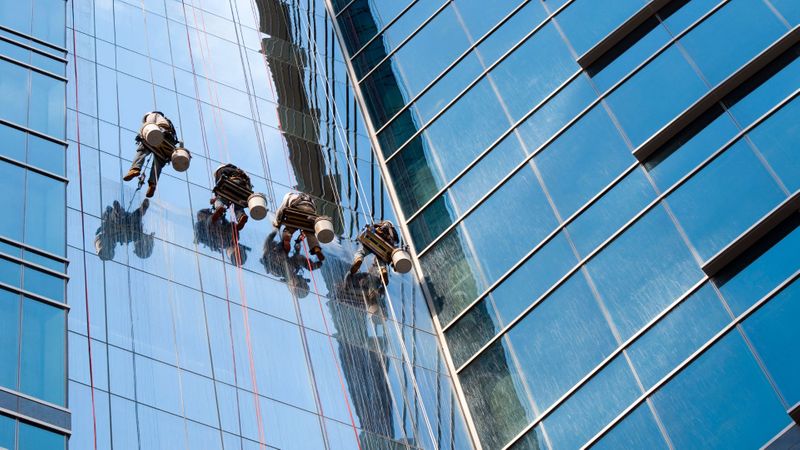 people cleaning a large building's windows