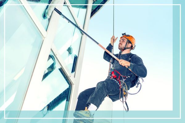 person cleaning windows on a tall building