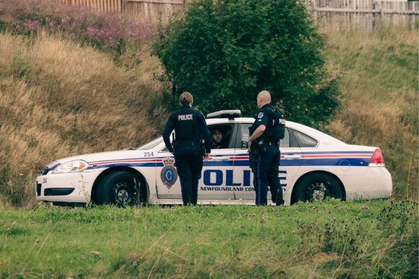 two police talking outside of police car