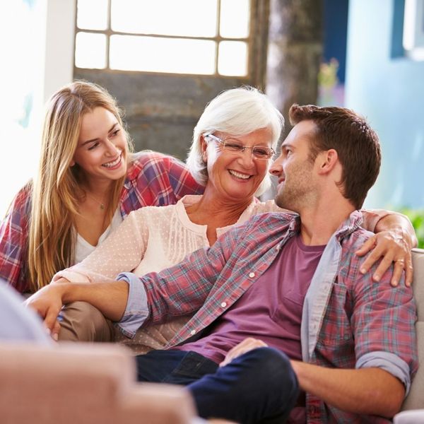 An image of an old woman happily sitting with her family.