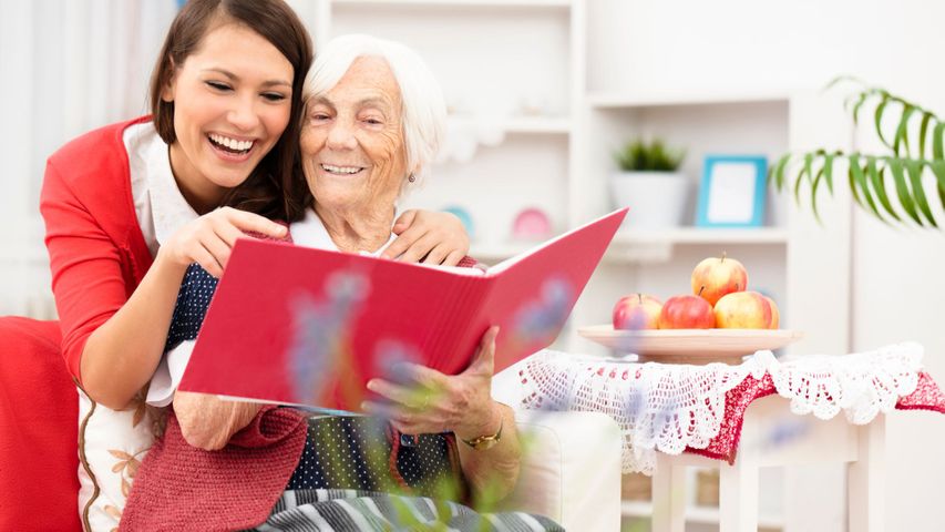 caregiver and elderly woman looking at photos 