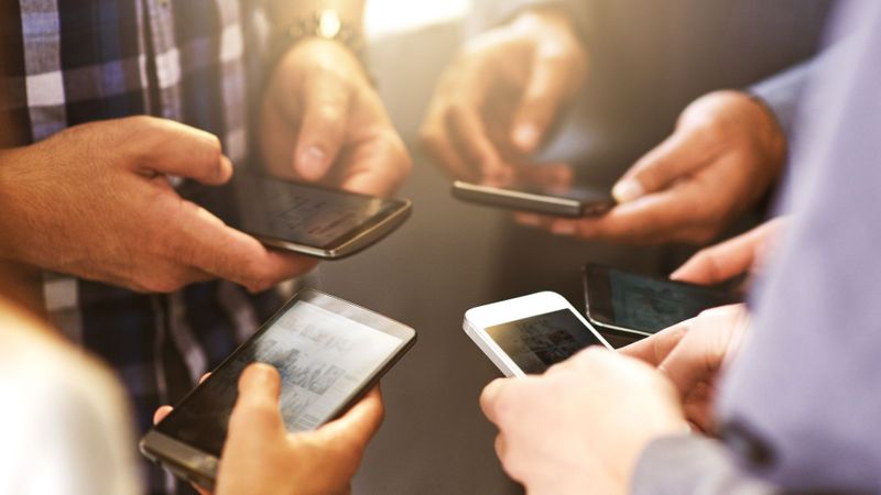 Group of people in a circle on their phones. 