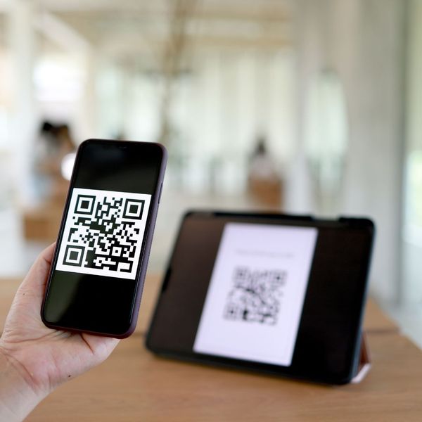 Person scanning a QR code from a tablet onto a phone. 