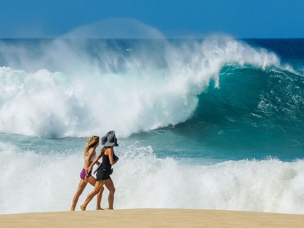 women walking next to big waves