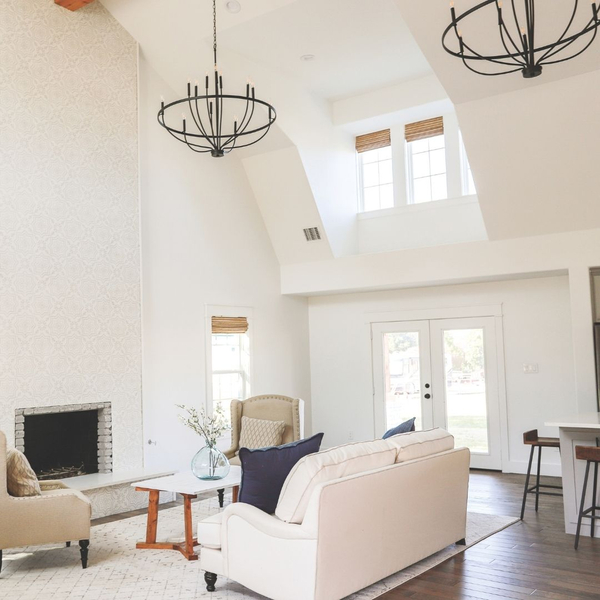 Bright living room with vaulted ceiling and black chandeliers.