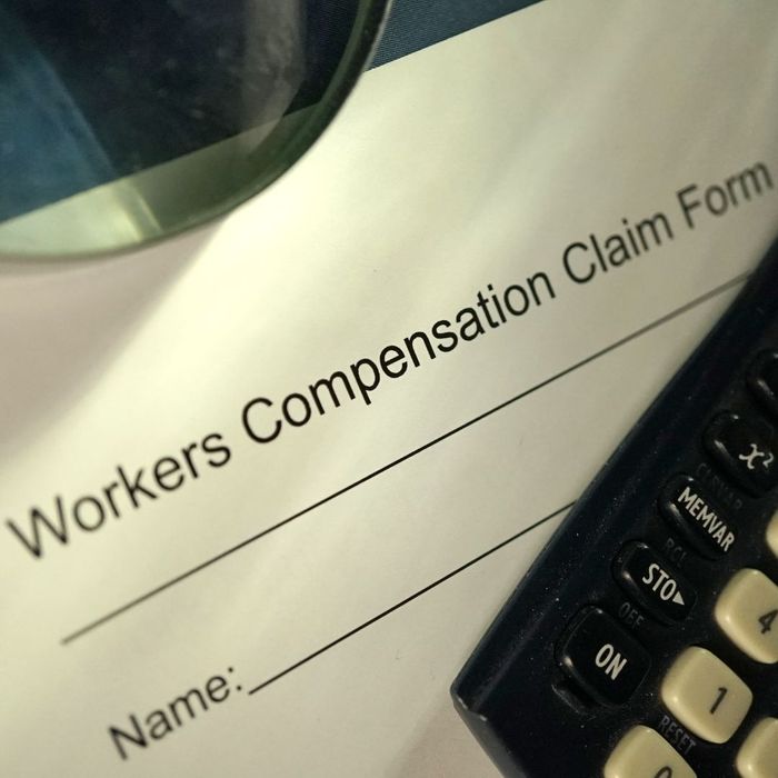 Workers Compensation Claim Form with a calculator on it. 
