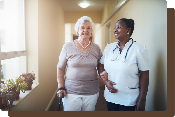 caregiver helping older woman down the hallway