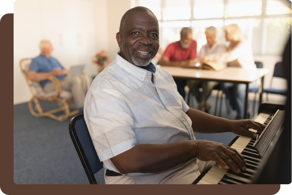 smiling older man sitting at a piano in a nursing home