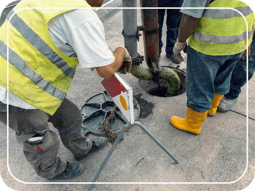 men working with sewer and manhole cover