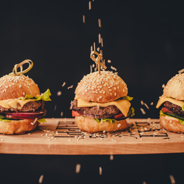 Trio of gourmet sliders with sesame seeds falling