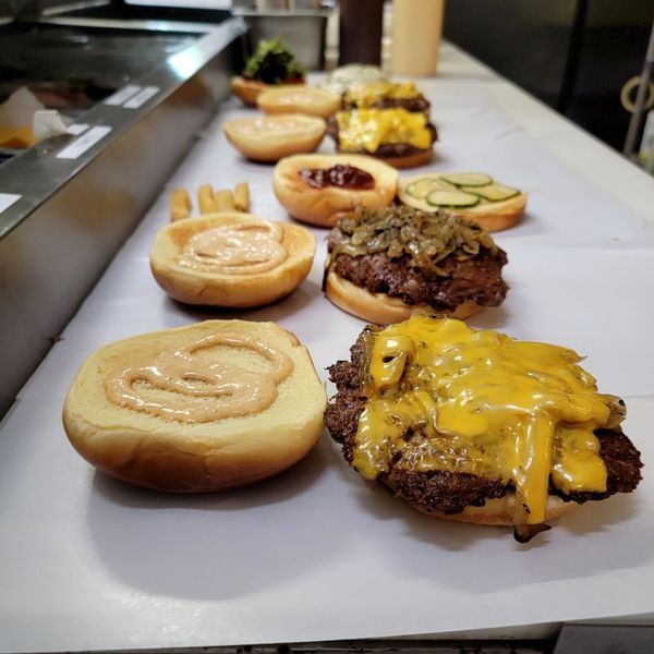burgers being topped in restaurant kitchen