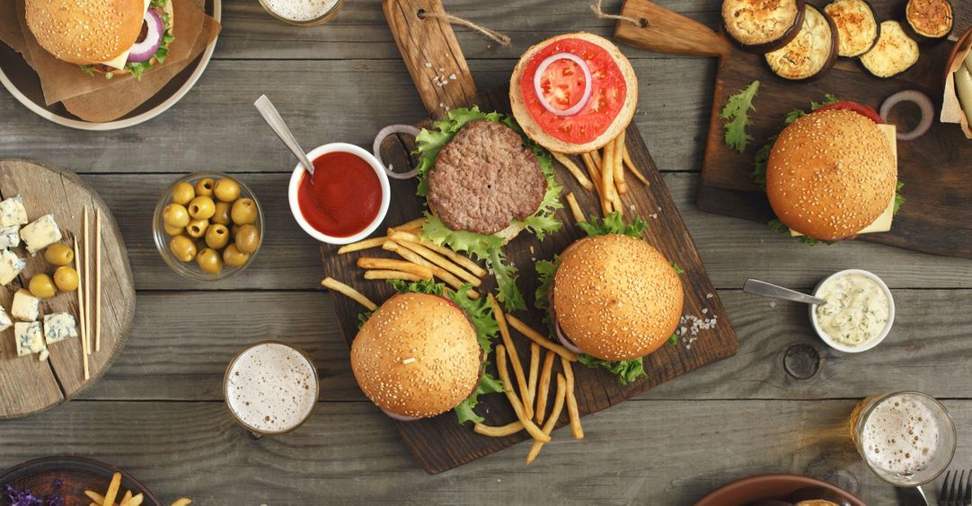 Top-down view of a burger spread with sides and condiments