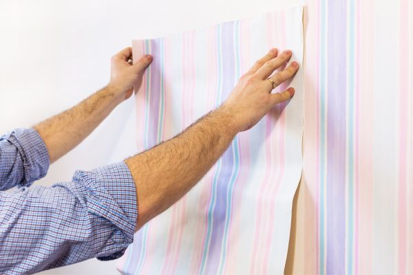 person putting up wallpaper