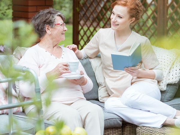 An image of a woman reading to an elderly woman.