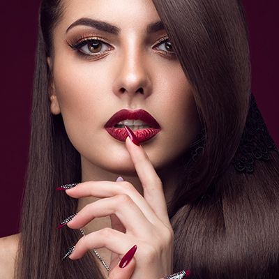 Photo of a model with red lipstick and red acrylic nails