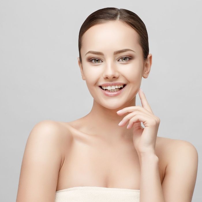 woman smiling with one finger on her face