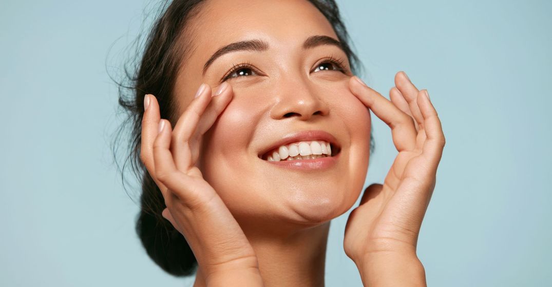 Woman smiling while gently touching the area under her eyes
