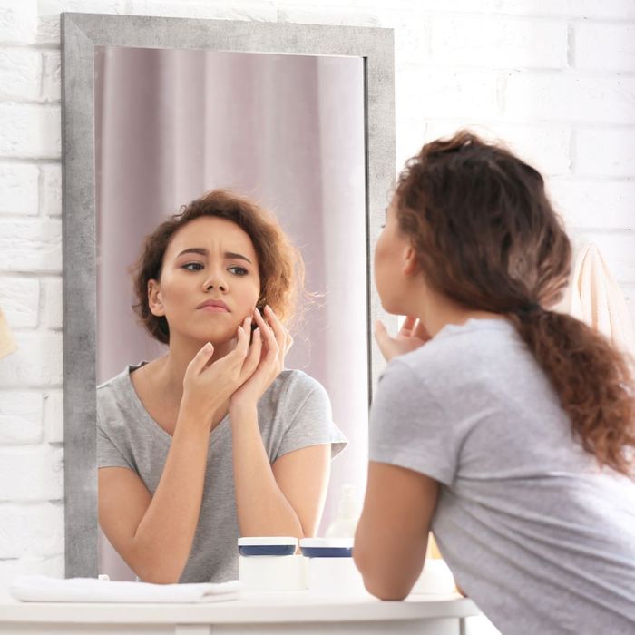 woman looking at her skin in the mirror