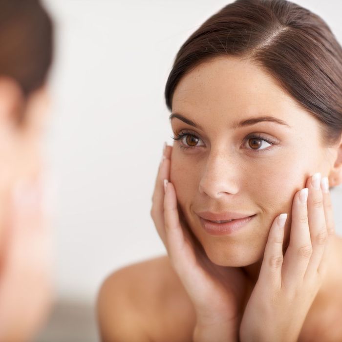 Woman looking at her face in the mirror