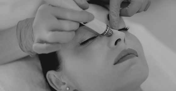 A black and white image of a woman getting a facial.