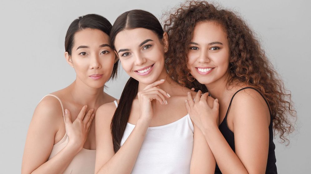 Three models with clear skin smiling for a photo