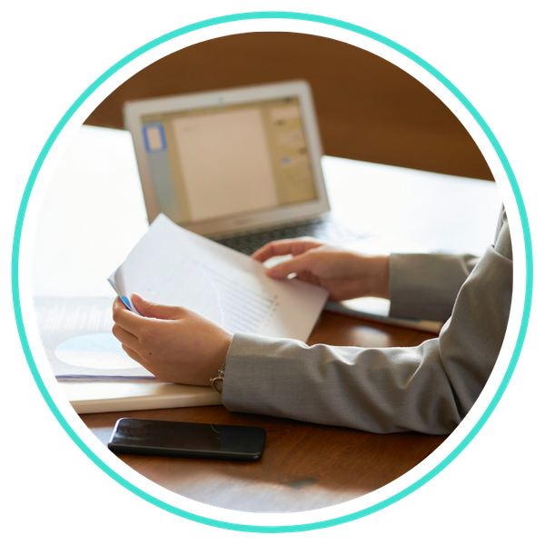 someone reviewing paperwork next to laptop