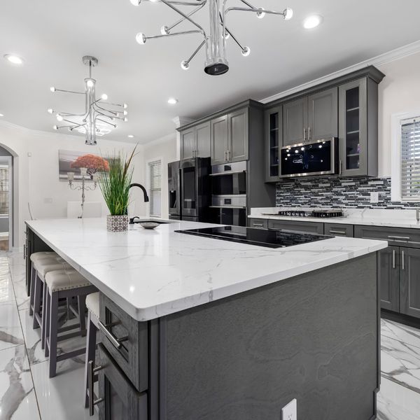 kitchen with contrasting accents featuring light coutertops and dark grey cabinets and island