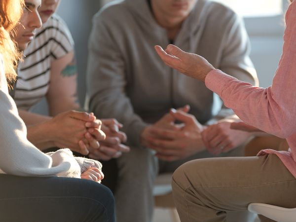 Close-up of people in a support group listening to someone talking.