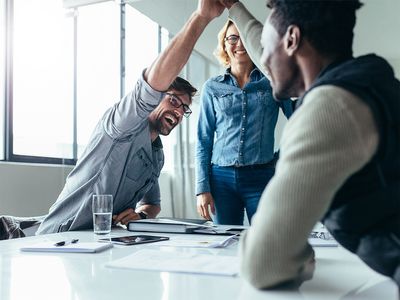 people high-fiving across a meeting table