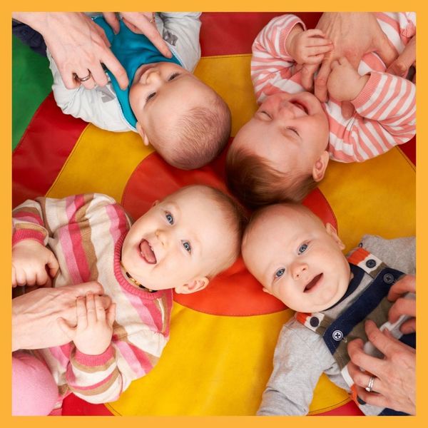 infants lying on rainbow mat