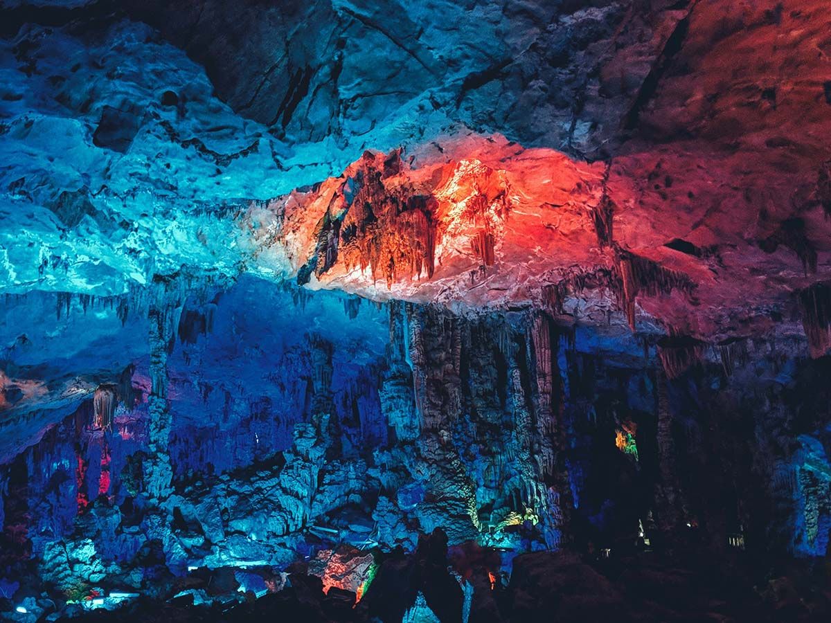 cave lit up with red and blue lights cave lit up with red and blue lights