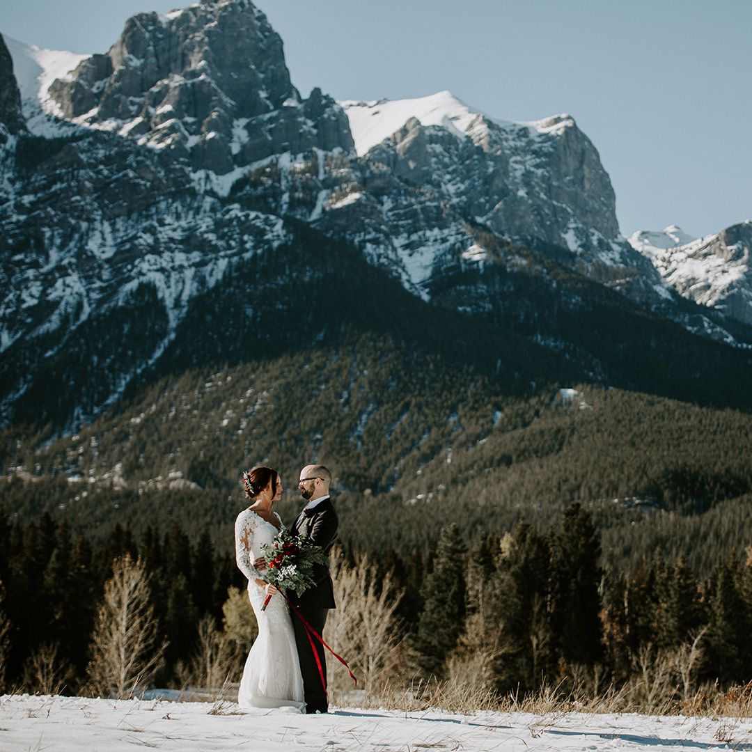 A bride and groom posing in front of a beautiful mountain backdrop