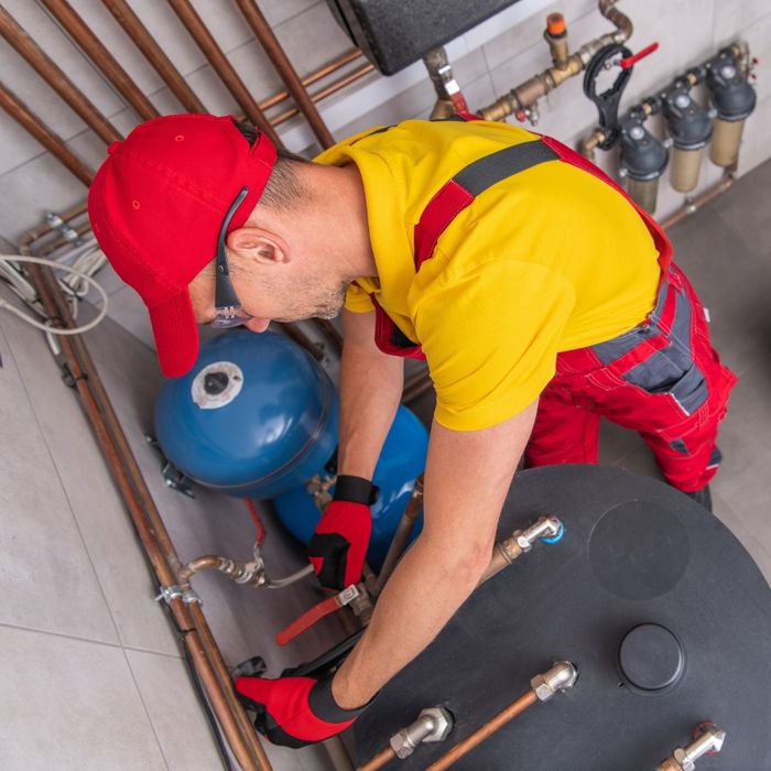 A plumber working on the gas lines leading into a water heater