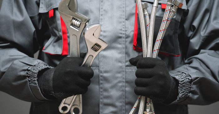 Plumber holding several tools and pipes